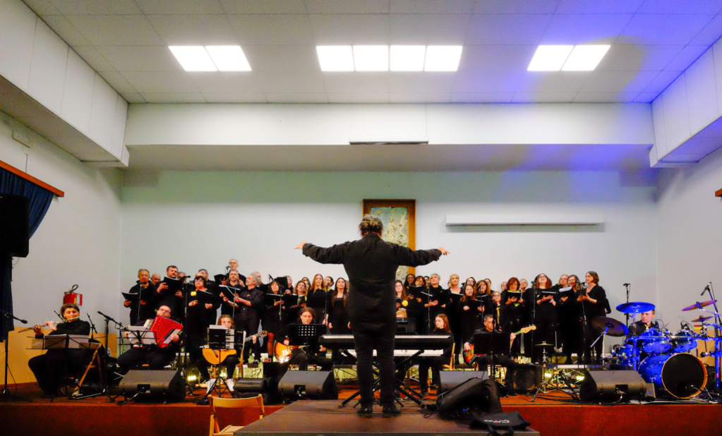 Coro DoreMimosa durante un’esibizione con direttore sul palco